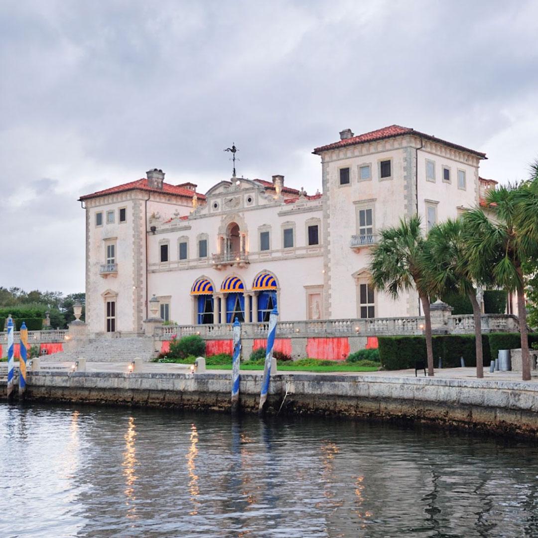 Historic waterfront mansion with palm trees and stone architecture