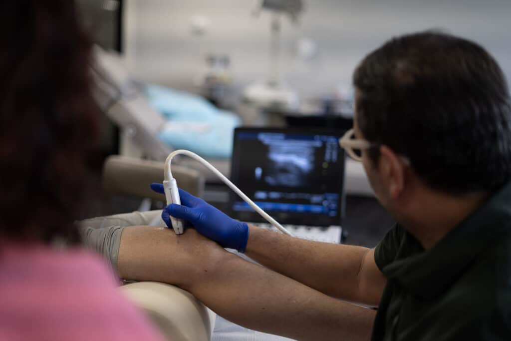 A provider scans with an ultrasound probe while watching the image on the screen