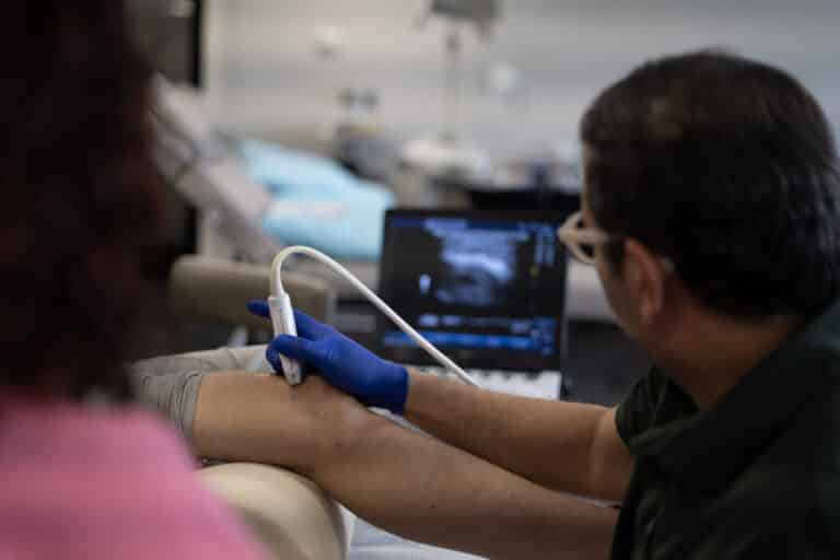 A provider scans with an ultrasound probe while watching the image on the screen